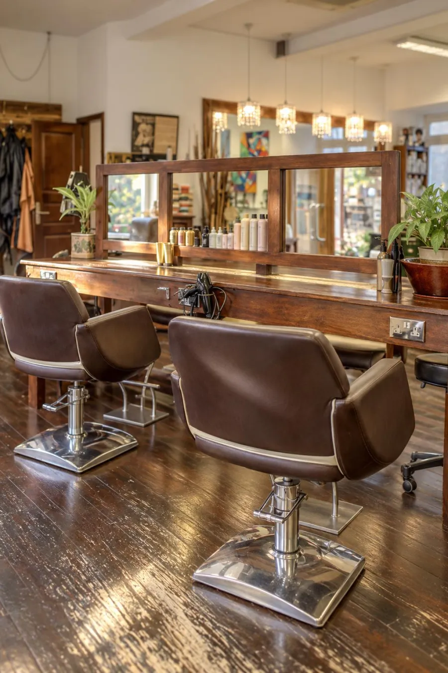 Brown leather chairs at Milano's long wooden styling table, with crystal pendant lights